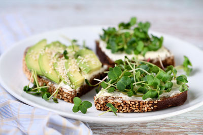 Sandwich rye bread with cereals, cream cheese, avocado and sprouted radish sprouts microgreen