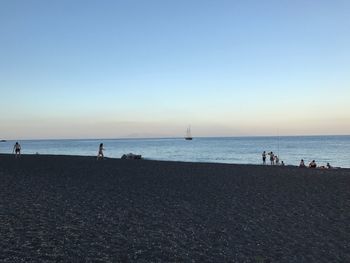 Silhouette people standing on beach against clear sky