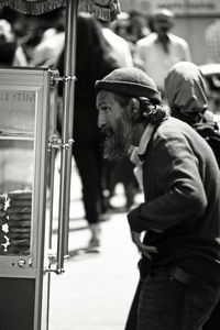 Side view of man wearing hat standing in city