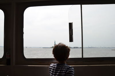 Rear view of boy looking through window