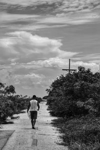 Rear view of woman walking on road against sky