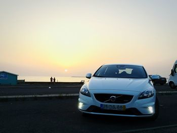 Cars on road against sky during sunset