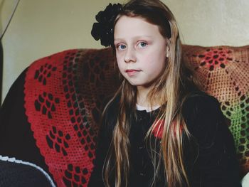 Portrait of girl sitting on sofa at home