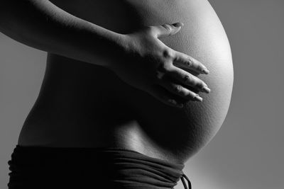 Midsection of woman touching hair against black background