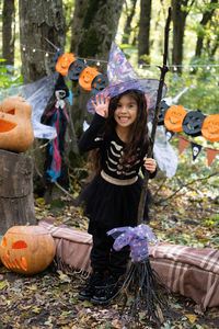 Arab girl in halloween costume and witch hat with broom in halloween decoration outdoor