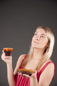 Woman holding coffee against black background
