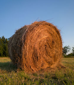 Hay bales on field against clear sky