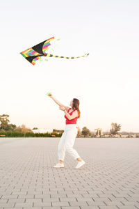 Full length of woman running flying against sky