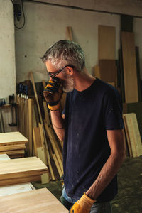 Midsection of man holding eyeglasses while standing at home
