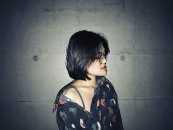 Portrait of woman standing against wall