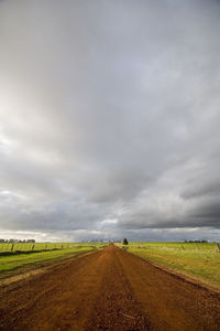 Road amidst field against sky