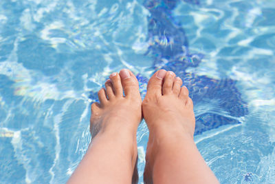 Low section of woman relaxing in swimming pool