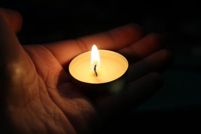 Cropped hands of person holding lit candle
