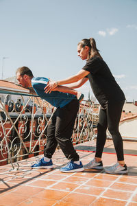 A couple doing training with rubber resistance band on their fooftop