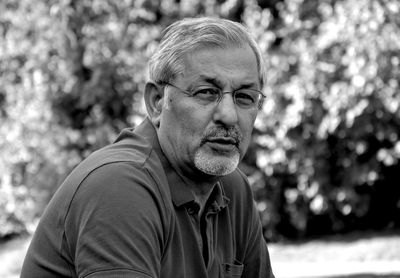 Portrait of man wearing eyeglasses sitting in park