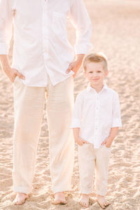 Portrait of boy standing with father at beach