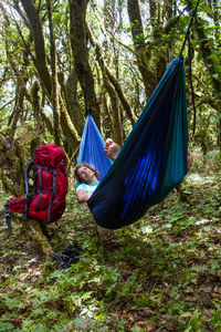 Woman in hammock against trees in forest