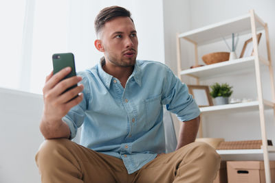 Young woman using mobile phone while sitting at home