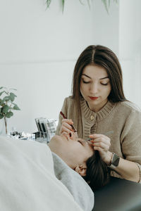 Portrait of a girl cosmetologist extending eyelashes to a woman.