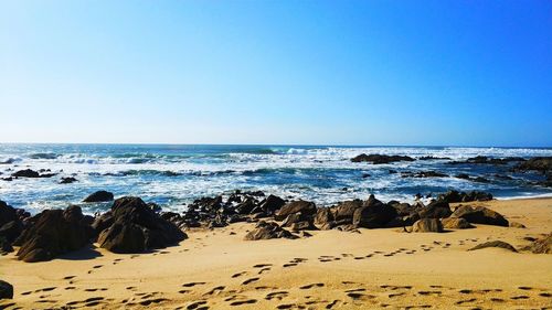 Scenic view of beach against clear blue sky