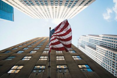 Low angle view of flag against buildings in city against sky