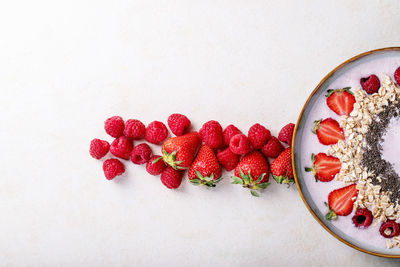 High angle view of red berries against white background