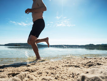 Low section of shirtless man on beach