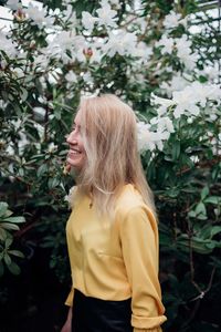 Smiling young woman standing by plants