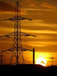 Silhouette of electricity pylon at sunset