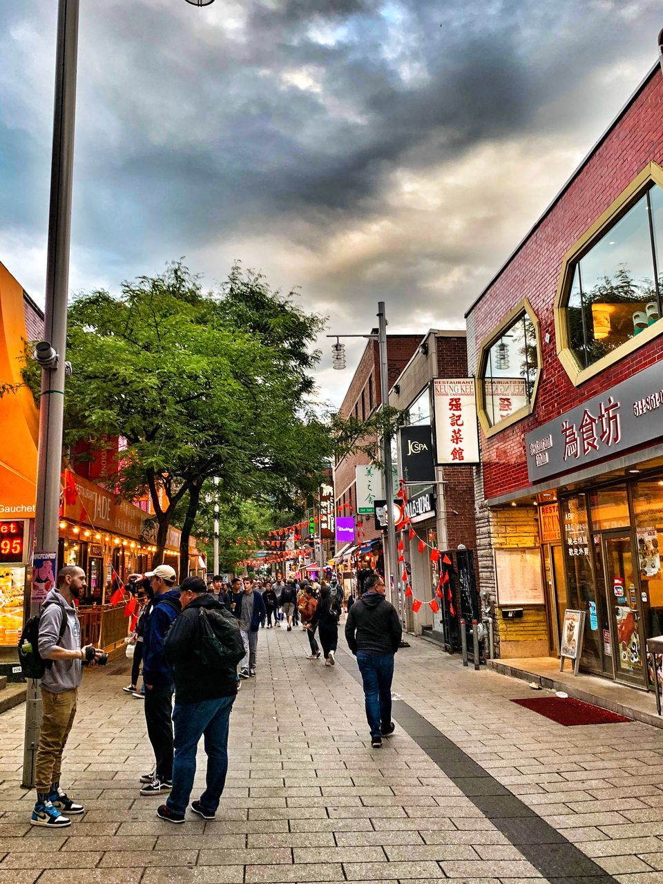 PEOPLE WALKING ON STREET AGAINST CLOUDY SKY