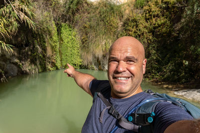 Portrait of young man standing against lake