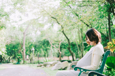 Side view of woman sitting in park