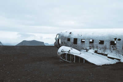 Abandoned airplane on mountain against cloudy sky