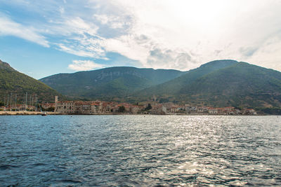 Scenic view of sea by mountains against sky