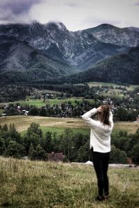 Woman standing on field with mountains in background