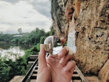 Close-up of cropped hand holding crystal ball with reflection