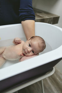 Cropped hand of mother bathing son in bathtub at home