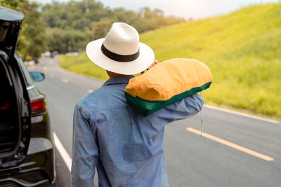 Rear view of man with umbrella standing on road