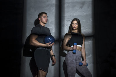 Young couple standing at gym against wall