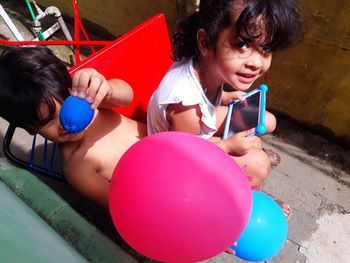 High angle portrait of siblings playing with balloons