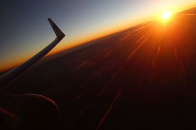 Silhouette airplane flying against sky during sunset