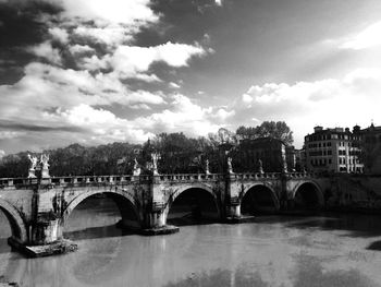 Arch bridge over river against sky in city