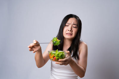 Young woman holding ice cream against white background