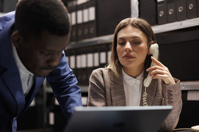 Young woman using mobile phone while sitting at office