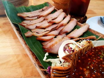 Pork grilled serve on wooden tray with banana leaf and dipping sauce