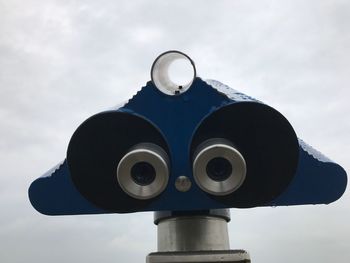 Low angle view of coin-operated binoculars against sky