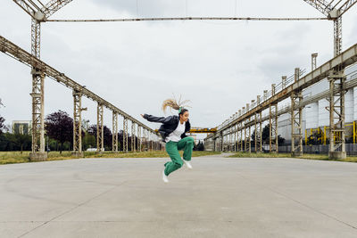 Happy young woman jumping on footpath