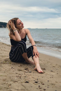 Side view of woman sitting at beach