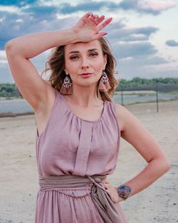 Portrait of beautiful young woman standing against sky