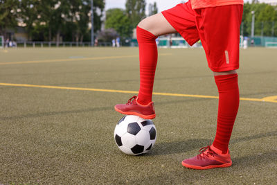 Unrecognizable soccer girl holding soccer ball with one foot sideways